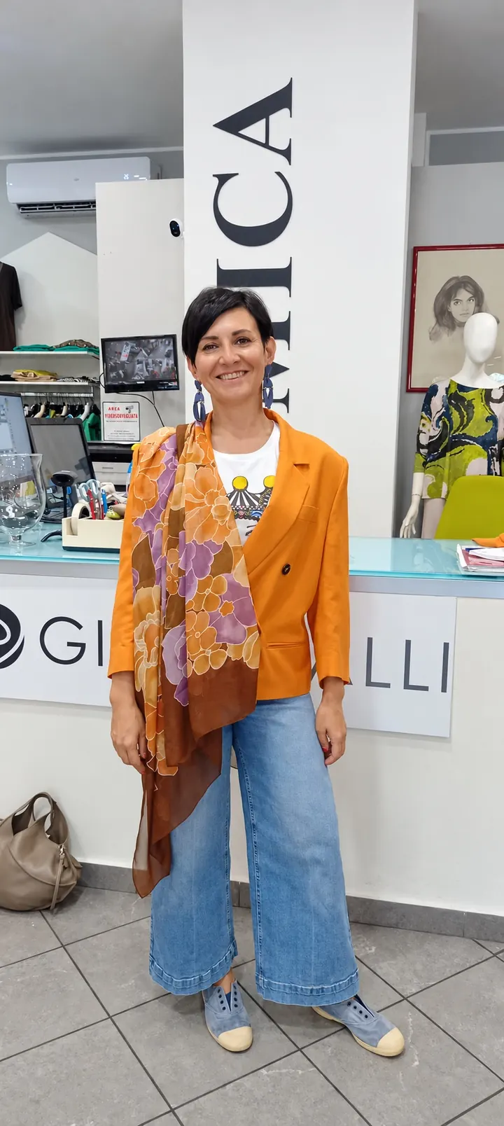 Cliente in boutique con una giacca arancio e un foulard