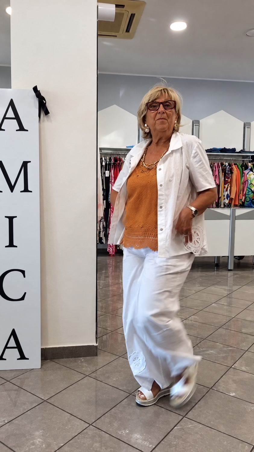 Cliente con un completo bianco accanto all’insegna Amica